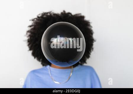 Nicht erkennbare ethnische Hipster weiblich mit Afro Frisur Blasen Kaugummi Beim Stehen gegen weiße Wand Stockfoto