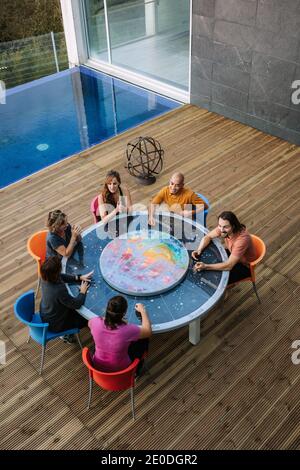 Von oben der Gruppe von Freunden, die um den Tisch auf sitzen Terrasse und miteinander reden, während das Wochenende zusammen genießen Stockfoto