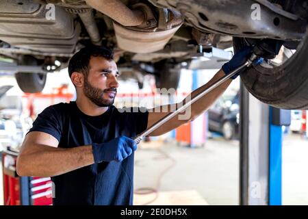 Fokussierte männliche Mechaniker mit Metallschlüssel Verschraubung Detail des Autos Rad während der Arbeit im Service Stockfoto