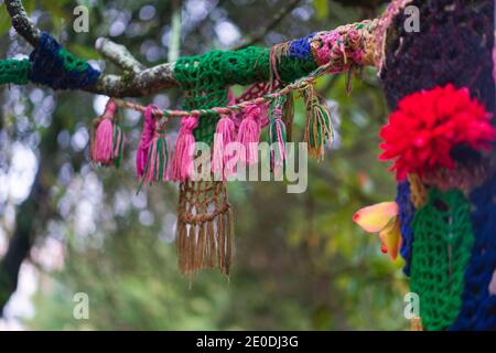 Bunte Häkeltextilien um einen Baum auf einem Waldpark Stockfoto