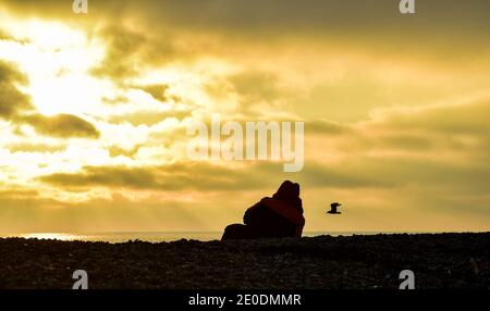 Brighton UK 31. Dezember 2020 - am Brighton Beach versammeln sich die Menschen, wenn die Sonne am 2020 an der Südküste von Großbritannien untergeht. Kredit Simon Dack / Alamy Live Nachrichten Stockfoto