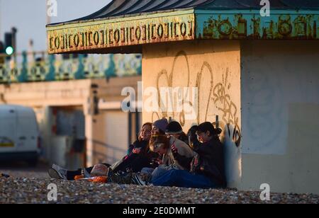 Brighton UK 31. Dezember 2020 - Junge Leute treffen sich am Brighton Strand, wenn die Sonne am 2020 an der Südküste von Großbritannien untergeht. Kredit Simon Dack / Alamy Live Nachrichten Stockfoto