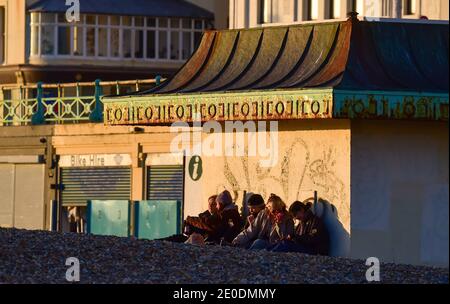 Brighton UK 31. Dezember 2020 - Junge Leute treffen sich am Brighton Strand, wenn die Sonne am 2020 an der Südküste von Großbritannien untergeht. Kredit Simon Dack / Alamy Live Nachrichten Stockfoto