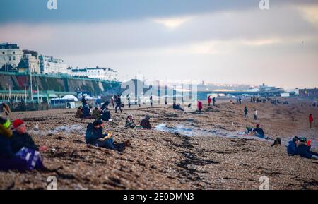 Brighton UK 31. Dezember 2020 - am Brighton Beach versammeln sich die Menschen, wenn die Sonne am 2020 an der Südküste von Großbritannien untergeht. Kredit Simon Dack / Alamy Live Nachrichten Stockfoto