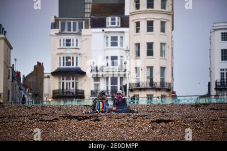 Brighton UK 31. Dezember 2020 - am Brighton Beach versammeln sich die Menschen, wenn die Sonne am 2020 an der Südküste von Großbritannien untergeht. Kredit Simon Dack / Alamy Live Nachrichten Stockfoto