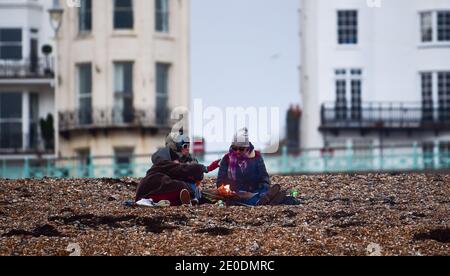 Brighton UK 31. Dezember 2020 - am Brighton Beach versammeln sich die Menschen, wenn die Sonne am 2020 an der Südküste von Großbritannien untergeht. Kredit Simon Dack / Alamy Live Nachrichten Stockfoto