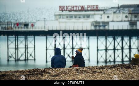 Brighton UK 31. Dezember 2020 - am Brighton Beach versammeln sich die Menschen, wenn die Sonne am 2020 an der Südküste von Großbritannien untergeht. Kredit Simon Dack / Alamy Live Nachrichten Stockfoto