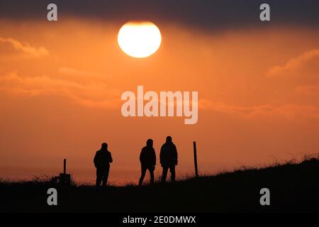 Cuckmere Haven, Seaford, Großbritannien. Dezember 2020. Die Sonne geht zum letzten Mal 2020 unter, während Wanderer die Aussicht von den Seven Sisters Cliffs in Sussex genießen.Quelle: James Boardman/Alamy Live News Stockfoto