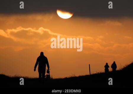 Cuckmere Haven, Seaford, Großbritannien. Dezember 2020. Die Sonne geht zum letzten Mal 2020 unter, während Wanderer die Aussicht von den Seven Sisters Cliffs in Sussex genießen.Quelle: James Boardman/Alamy Live News Stockfoto