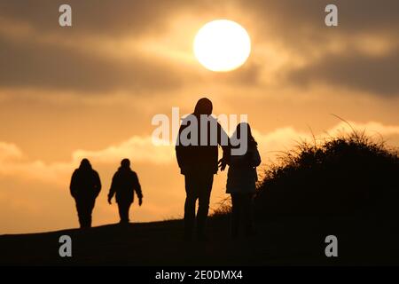 Cuckmere Haven, Seaford, Großbritannien. Dezember 2020. Die Sonne geht zum letzten Mal 2020 unter, während Wanderer die Aussicht von den Seven Sisters Cliffs in Sussex genießen.Quelle: James Boardman/Alamy Live News Stockfoto