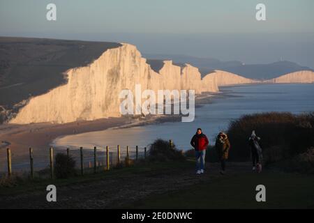 Cuckmere Haven, Seaford, Großbritannien. Dezember 2020. Die Sonne geht zum letzten Mal 2020 unter, während Wanderer die Aussicht von den Seven Sisters Cliffs in Sussex genießen.Quelle: James Boardman/Alamy Live News Stockfoto