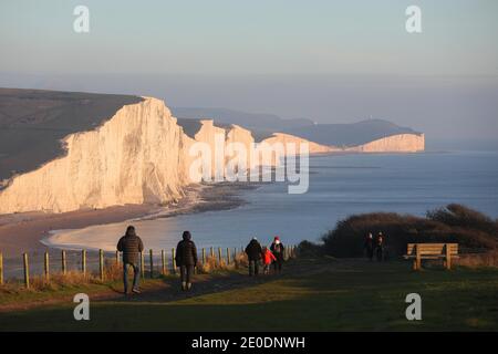 Cuckmere Haven, Seaford, Großbritannien. Dezember 2020. Die Sonne geht zum letzten Mal 2020 unter, während Wanderer die Aussicht von den Seven Sisters Cliffs in Sussex genießen.Quelle: James Boardman/Alamy Live News Stockfoto