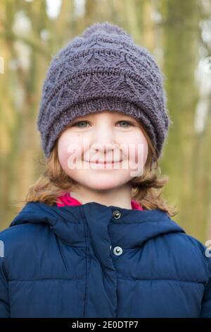 Junges Mädchen im Alter von 6 Jahren, trägt einen Wolle / Wollbommel Hut während einer Familie Winterspaziergang über West End Common, Esher, in Surrey, Großbritannien. (122) Stockfoto