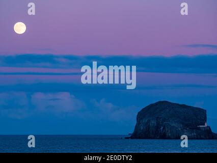 Ein Vollmond erhebt sich über Bass Rock Island mit einem bunten Sonnenuntergang, Firth of Forth, Schottland, Großbritannien Stockfoto