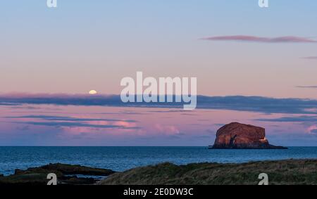 Ein Vollmond erhebt sich über Bass Rock Island mit einem bunten Sonnenuntergang, Firth of Forth, Schottland, Großbritannien Stockfoto