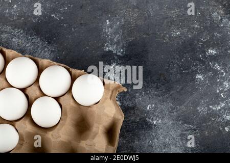 Rohe Hühnereier in Eierbox auf Marmorboden Stockfoto