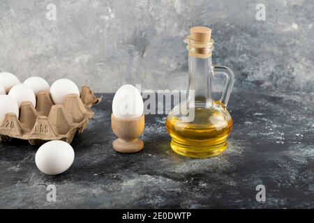 Rohes Hühnerei in Eierbecher mit Eierkarton auf Marmor Hintergrund Stockfoto