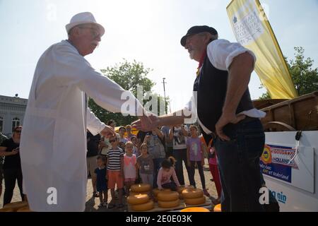 Nach einer Verhandlung schließen der Käsemarkt und der Landwirt den Deal, indem sie sich gegenseitig die Hände auf dem Gouda Käsemarkt schlagen. Stockfoto