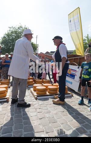 Nach einer Verhandlung schließen der Käsemarkt und der Landwirt den Deal, indem sie sich gegenseitig die Hände auf dem Gouda Käsemarkt schlagen. Stockfoto