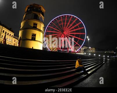 Düsseldorf, Deutschland. Dezember 2020. Eine alleinerziehende Dame sitzt auf der Treppe am Burgplatz in der Altstadt. Wo es meist viele Menschen gibt, ist es wegen der Maßnahmen gegen das Corona-Virus zum Jahreswechsel ruhig. Quelle: Roberto Pfeil/dpa/Alamy Live News Stockfoto