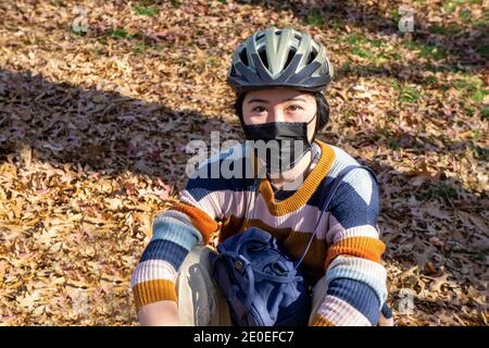 Teen Girl trägt Fahrradhelm und Schutzmaske, halblanges sitzendes Portrait Stockfoto