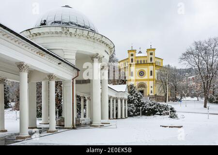 Marianske Lazne, Tschechische Republik - Dezember 29 2020: Winterlandschaft der christlichen Kirche der Übernahme von Maria, Rudolph und Caroline Frühling Kolonnade. Stockfoto