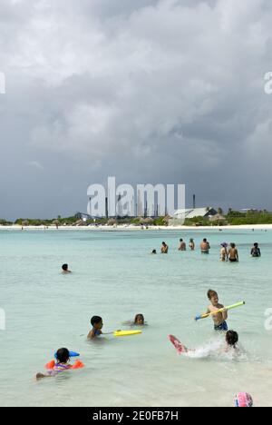 Baby Beach ist eine flache, geschützte Lagune in Seroe Colorado, an der Südostküste von Aruba, mit der Valero Ölraffinerie in Sicht. Stockfoto