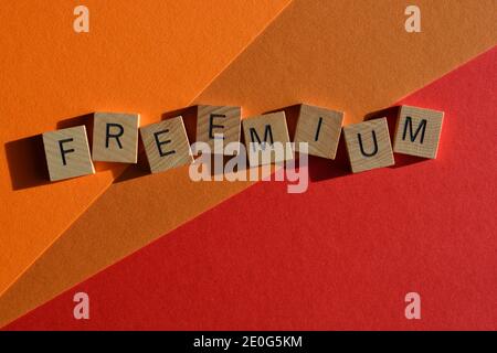 Freemium, Marketing-Slogan, eine Kombination aus Free und Premium, in Holzbuchstaben isoliert auf rotem und orangefarbenem Hintergrund Stockfoto