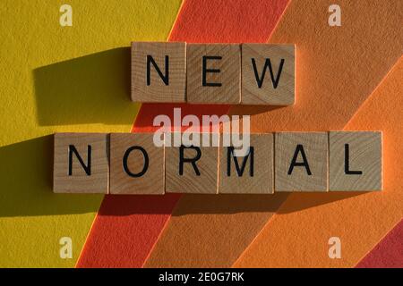 Neue normale, Wörter in hölzernen Buchstaben Alphabet isoliert auf buntem Hintergrund Stockfoto