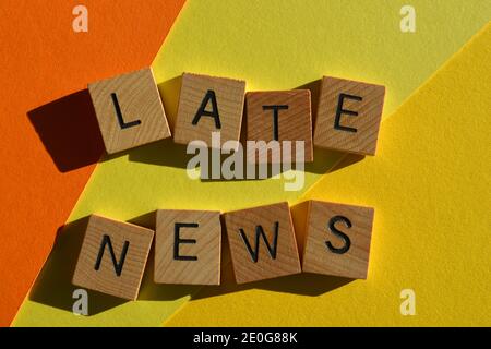 Späte Nachrichten, Wörter in hölzernen Buchstaben Alphabet isoliert auf gelbem und orangefarbenem Hintergrund Stockfoto