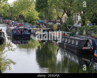 Die Electric Barge, ein Partyboot im Londoner Little Venice Basin, passiert Hausboote entlang der Blomfield Road auf dem Regent's Canal in London, W9 Stockfoto