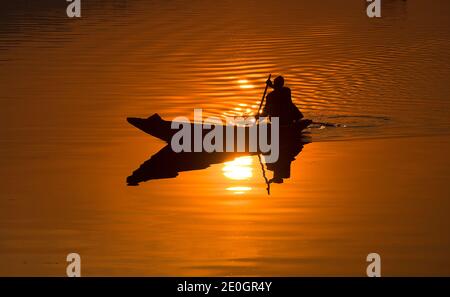 Srinagar, indisch kontrolliertes Kaschmir. Dezember 2020. Ein Bootsmann rudert sein Boot bei Sonnenuntergang in Srinagar, der Sommerhauptstadt von indisch-kontrolliertem Kaschmir, Dec. 31, 2020. Quelle: Javed Dar/Xinhua/Alamy Live News Stockfoto