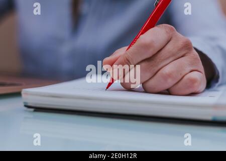 Weibliche Hände mit einem roten Stift schreiben auf Notebook. Stockfoto