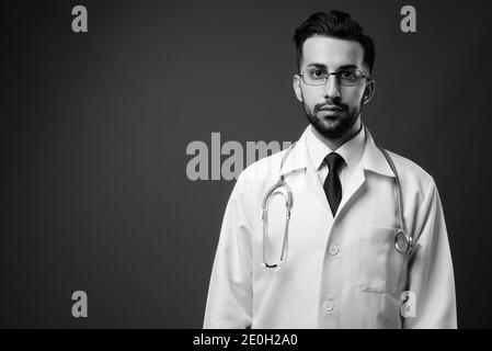 Junge gut aussehende bärtige iranische Mann Arzt in schwarz und erschossen Weiß Stockfoto