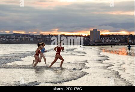 Portobello, Edinburgh, Schottland, Großbritannien. Januar 2021. Neujahrstag Dip bei Sonnenaufgang, Temperatur 1 Grad Celsius. Porty Loony Dook nicht stattfinden aufgrund der Pandemie so separate Gruppen genießen ihre eigenen Neujahr schwimmen im Firth of Forth. Quelle: Arch White/Alamy Live News. Stockfoto