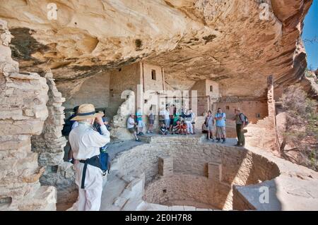 Parkführer und Besucher über Kiva (zeremonielle Kammer) im Balcony House Cliff Dwelling, Cliff Palace Loop, Mesa Verde National Park, Colorado, USA Stockfoto