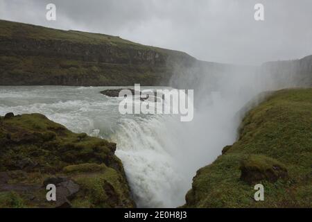 Menschen, die die Kraft des beliebten Touristenziels besuchen und erleben - Gullfoss Wasserfall auf Hvita Fluss in Island. Stockfoto