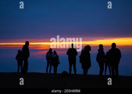 Menschen beobachten den Sonnenaufgang am Neujahrstag 2021 vom Glastonbury Tor, Somerset Stockfoto