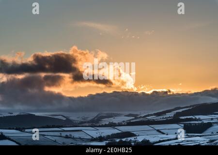 Der letzte Sonnenuntergang von 2020 über der verschneiten Landschaft von Mid-Wales, gesehen vom Offa's Dyke Fußweg in der Nähe von Knighton, Powys, UK am Silvesterabend, 2020 Stockfoto