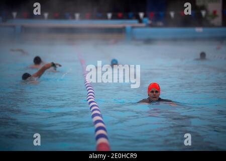 Am frühen Morgen Schwimmer in einer Schneedusche bei Null-Grad-Temperaturen in Charlton Lido in Hornfair Park, London. Stockfoto