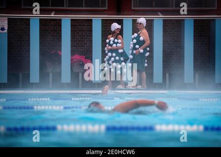 Jessica Walker und Nicola Foster, bekannt als die Lido Ladies, bereiten sich auf ein frühmorgendliches Schwimmen bei einer Schneedusche im Charlton Lido im Hornfair Park, London, vor. Stockfoto