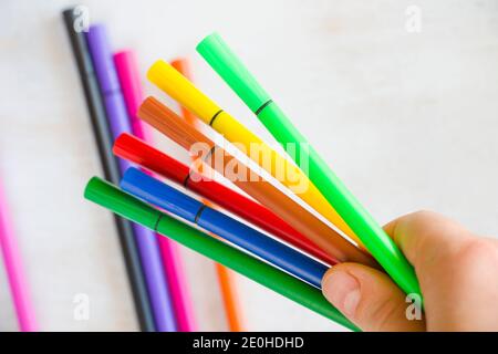 Große Gruppe von farbigen Zeichenmarkierungen zum Skizzieren hält in der Hand, auf dem weißen Hintergrund Stockfoto