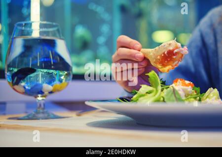 In einem Fischrestaurant hält der Mann eine Krabbenklaue in der Hand. Abendessen in einem gemütlichen Fischcafe Stockfoto