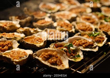 Nahaufnahme vieler Austern auf dem Grill. Köstliche gegrillte Austern Stockfoto