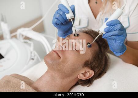 Nahaufnahme eines männlichen Klienten, der Elektrolyse Gesichtshaut bekommt Behandlung im Schönheitssalon Stockfoto