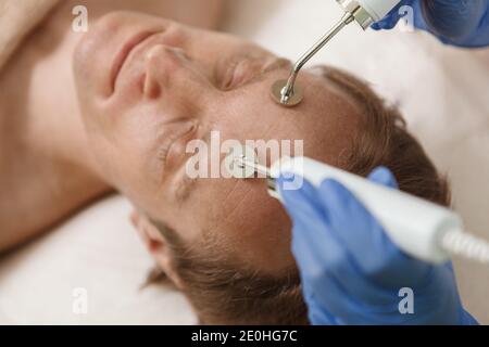 Nahaufnahme eines männlichen Kunden genießen Hardware Hautpflege Gesichtsbehandlung In dermatologischen Klinik Stockfoto