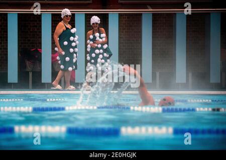 Jessica Walker und Nicola Foster, bekannt als die Lido Ladies, bereiten sich auf ein frühes Schwimmen während einer kurzen Schneedusche im Charlton Lido im Hornfair Park, London, vor. Stockfoto