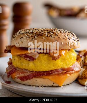 Nahaufnahme eines Frühstückssandwiches mit Ei, Speck und Käse auf einem Bagel Stockfoto