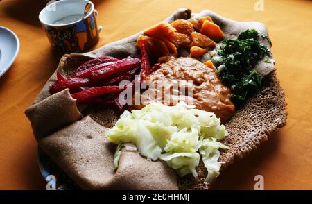 Traditionelles Gericht von gemischten Gemüseprobenehmern auf einem Bett von Injera Fladenbrot Stockfoto