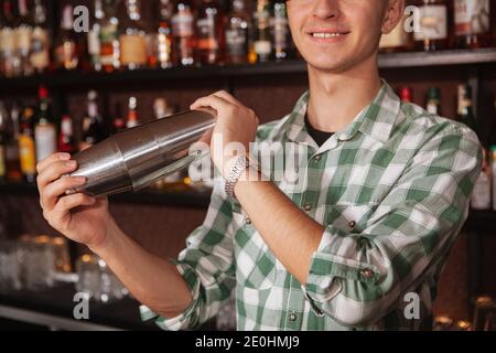 Nahaufnahme eines nicht erkennbaren männlichen Barkeepers, der ein Getränk für einen Kunden vorbereitet, mit Shaker-Dose Stockfoto